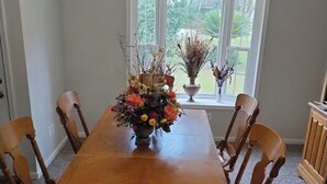 A dining room with a wooden table, six chairs, a chandelier, and a window with a view of greenery. - Karen’s Cove
Charming 2-bedroom house in terrific Darien with WiFi, AC (Darien)