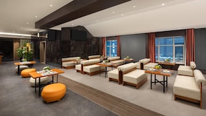 Een moderne hotellobby met verschillende zithoeken, inclusief banken en tafels, in een ruim opgezette indeling.