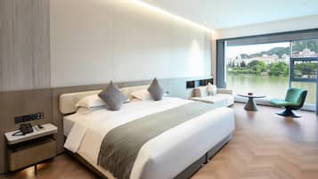 A modern hotel room with a large bed, bedside tables, a small table, and a chair.