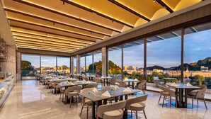A modern restaurant with a high ceiling and large windows offering a city view. - Wyndham Garden Liuzhou Wuxing Street (Liuzhou)