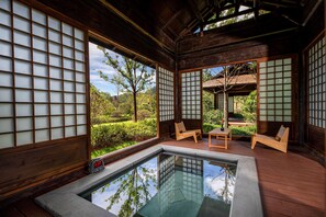 Una habitación tradicional japonesa con suelo de tatami, una pequeña mesa de madera y un área de descanso con esterillas de tatami.