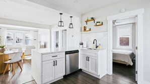 A modern kitchen with white cabinetry, a dishwasher, and a dining area with a wooden table and chairs. - Charming 2-bedroom condo in marvelous Chicago (Chicago)