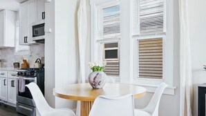 A modern kitchen with white cabinets, a wooden dining table, and two white chairs. - Charming 2-bedroom condo in marvelous Chicago (Chicago)