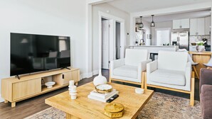A modern living room with a flat-screen TV, a coffee table, and two white armchairs. - Charming 2-bedroom condo in marvelous Chicago (Chicago)