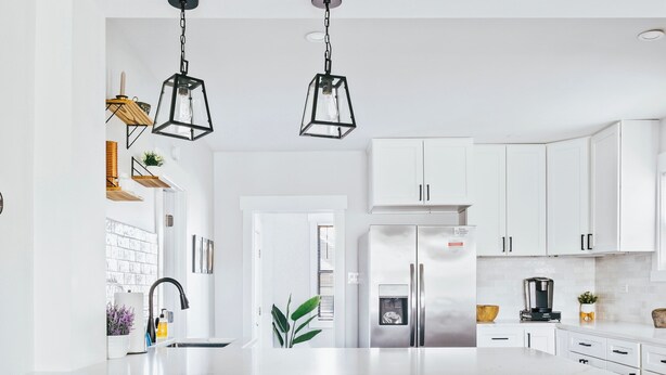 A modern kitchen with a large island, black stools, white cabinets, and hanging pendant lights. - Charming 2-bedroom condo in marvelous Chicago (Chicago)