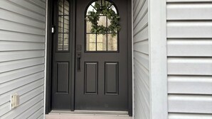 Un ingresso con ghirlanda, una porta nera e un piccolo portico.