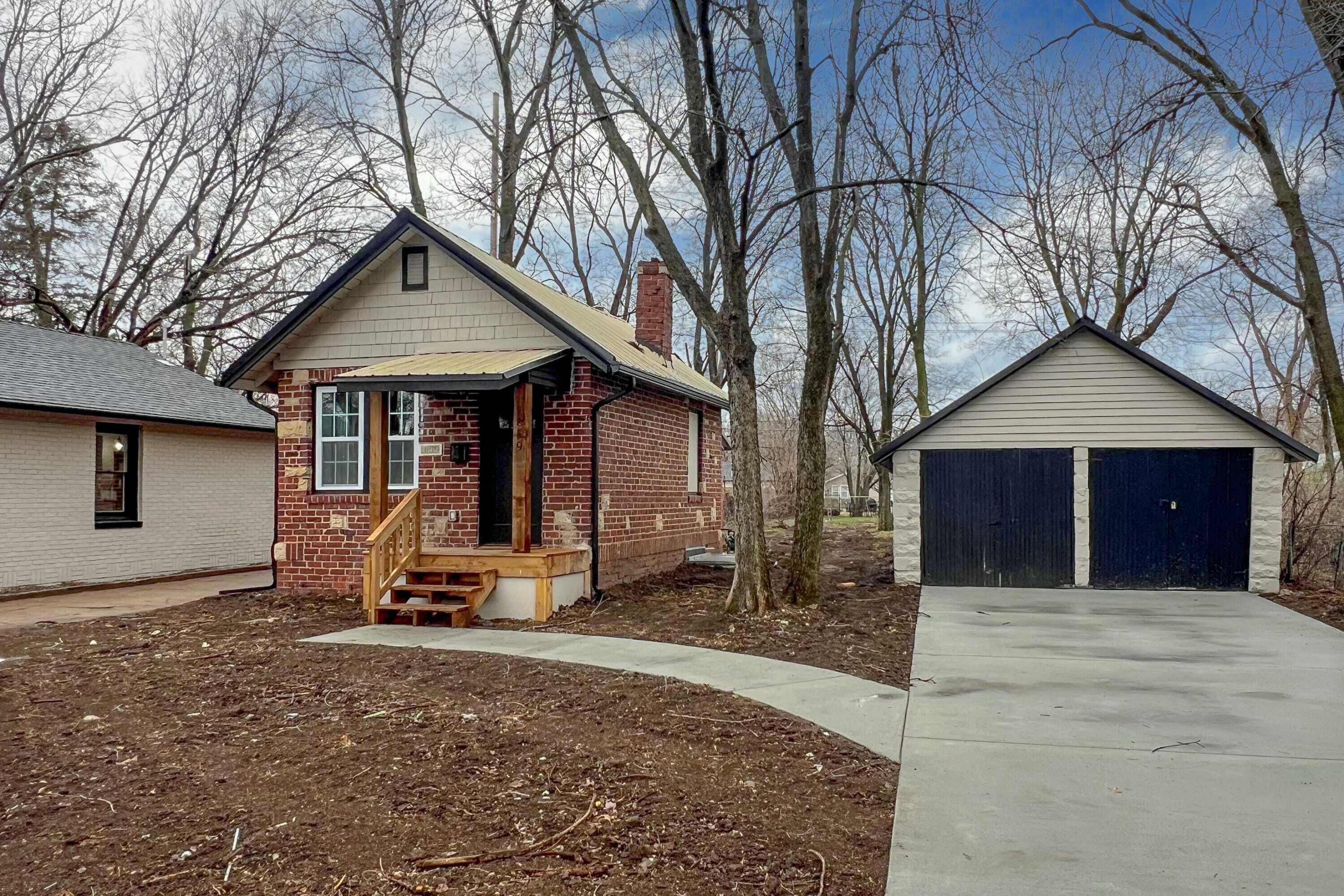 A residential property with a brick house, a wooden porch, and a garage.
