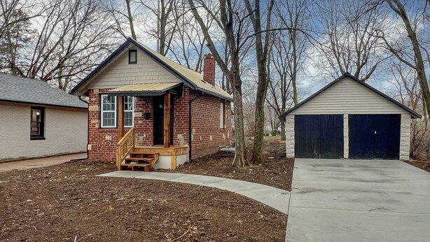 Ein Wohnhaus mit Ziegelhaus, Holzveranda und Garage.