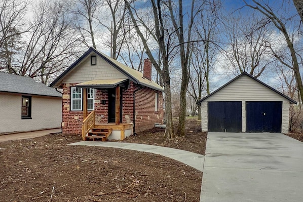 A residential property with a brick house, a wooden porch, and a garage.