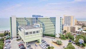 A hotel with a modern design, featuring a large parking lot and a view of the ocean.