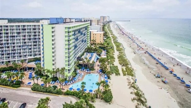 A hotel with a pool, beach, and ocean view.