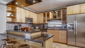 A modern kitchen with a central island, stainless steel appliances, and wooden cabinetry. - Villa Beryl - Lux 4BR/3BA - Rooftop Deck (San Diego)