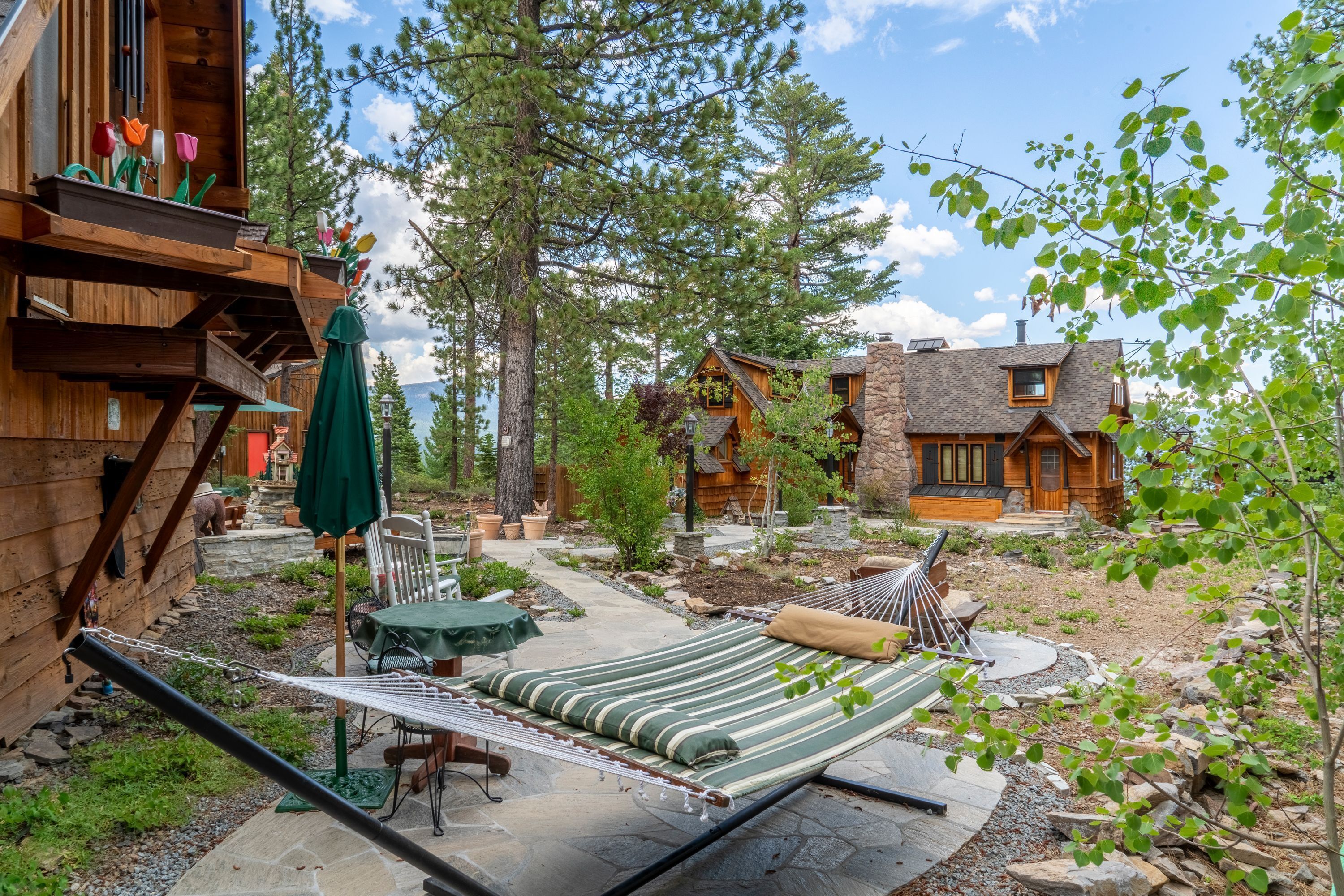 A wooden cabin with a hammock, outdoor seating, and a stone patio.