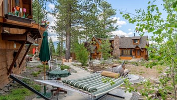 A wooden cabin with a hammock, outdoor seating, and a stone patio.