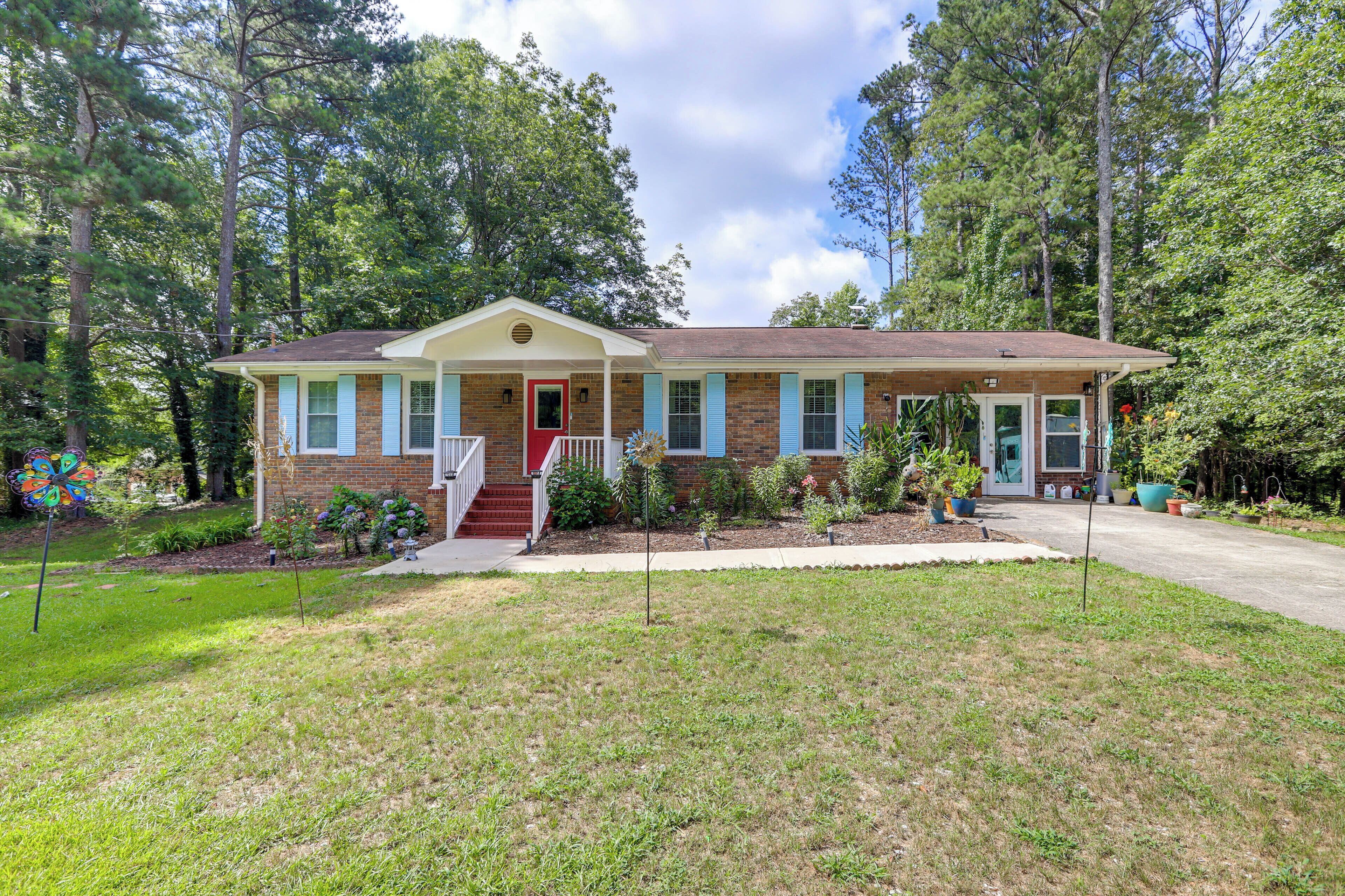 A single-story house with a front porch, brick exterior, and blue shutters.