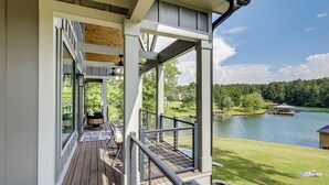 Eine überdachte Terrasse mit Blick auf einen See und ein Haus im Hintergrund.