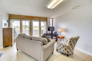 A living room with a sofa, armchair, TV, and desk. - Swim, Fish & Suntan: Cozy Corpus Christi Retreat (Corpus Christi)