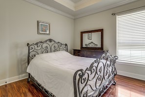 A bedroom with a bed, dresser, mirror, and a window with blinds.