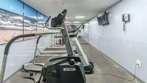 A gym with treadmills, a wall-mounted TV, and a phone on the wall.