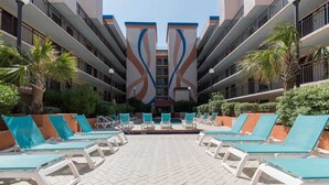 A poolside area with lounge chairs and palm trees.