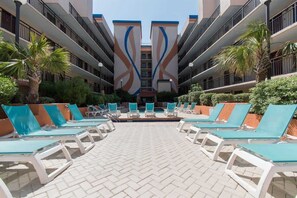 A poolside area with lounge chairs and palm trees.