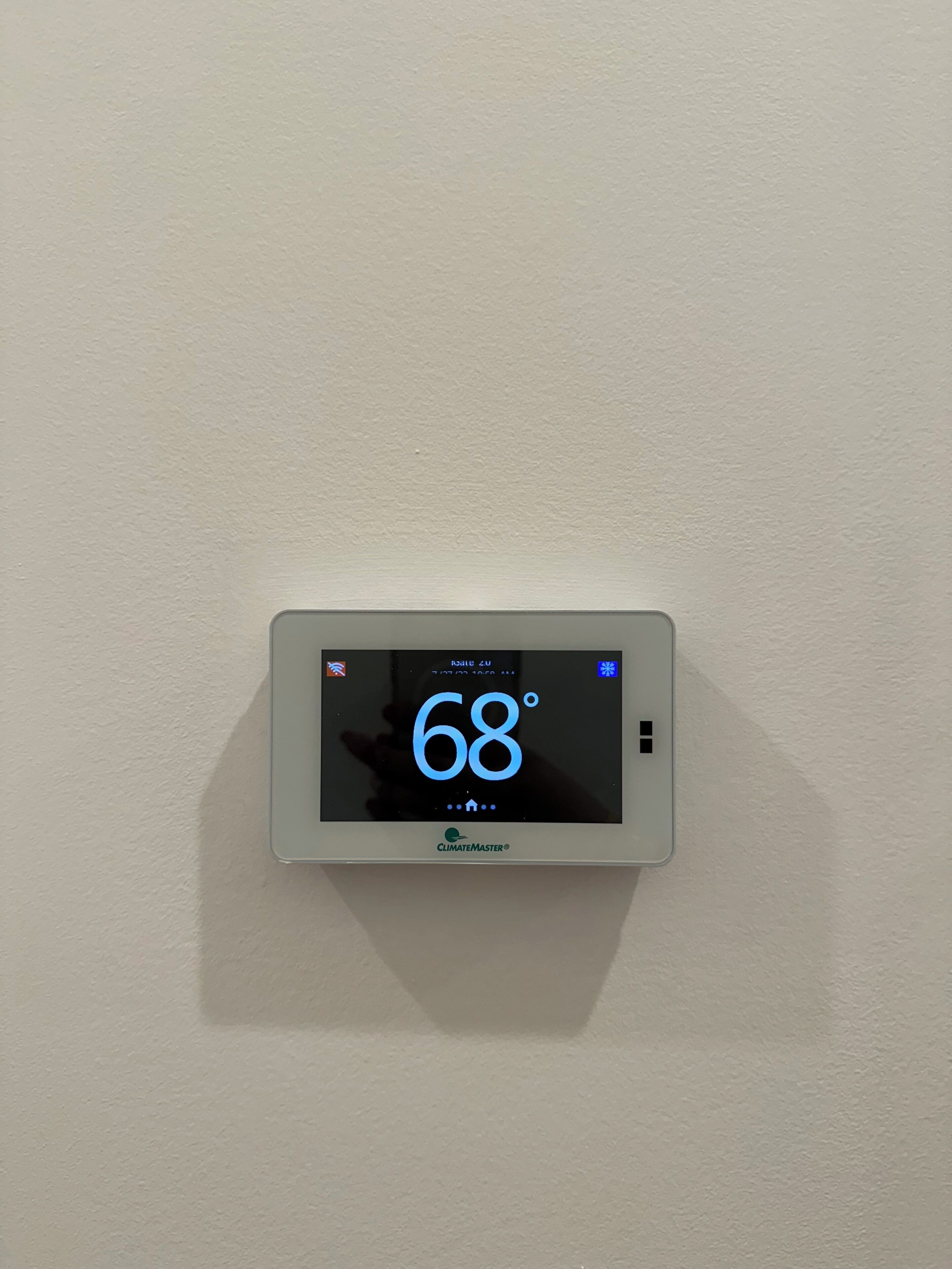 A digital thermostat displaying 68 degrees Fahrenheit on a white wall.