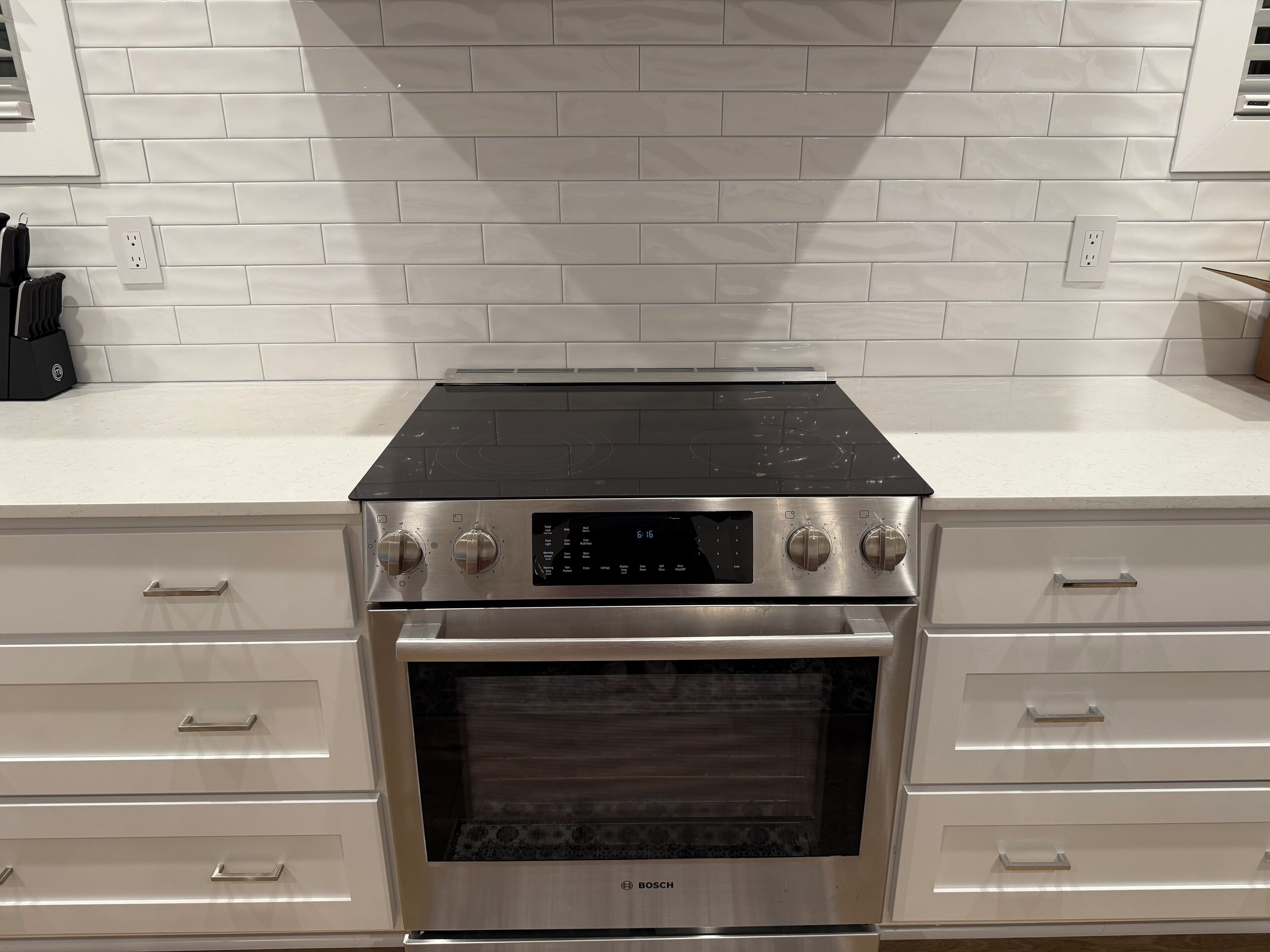 Uma cozinha com fogão de aço inoxidável, forno e armários brancos.