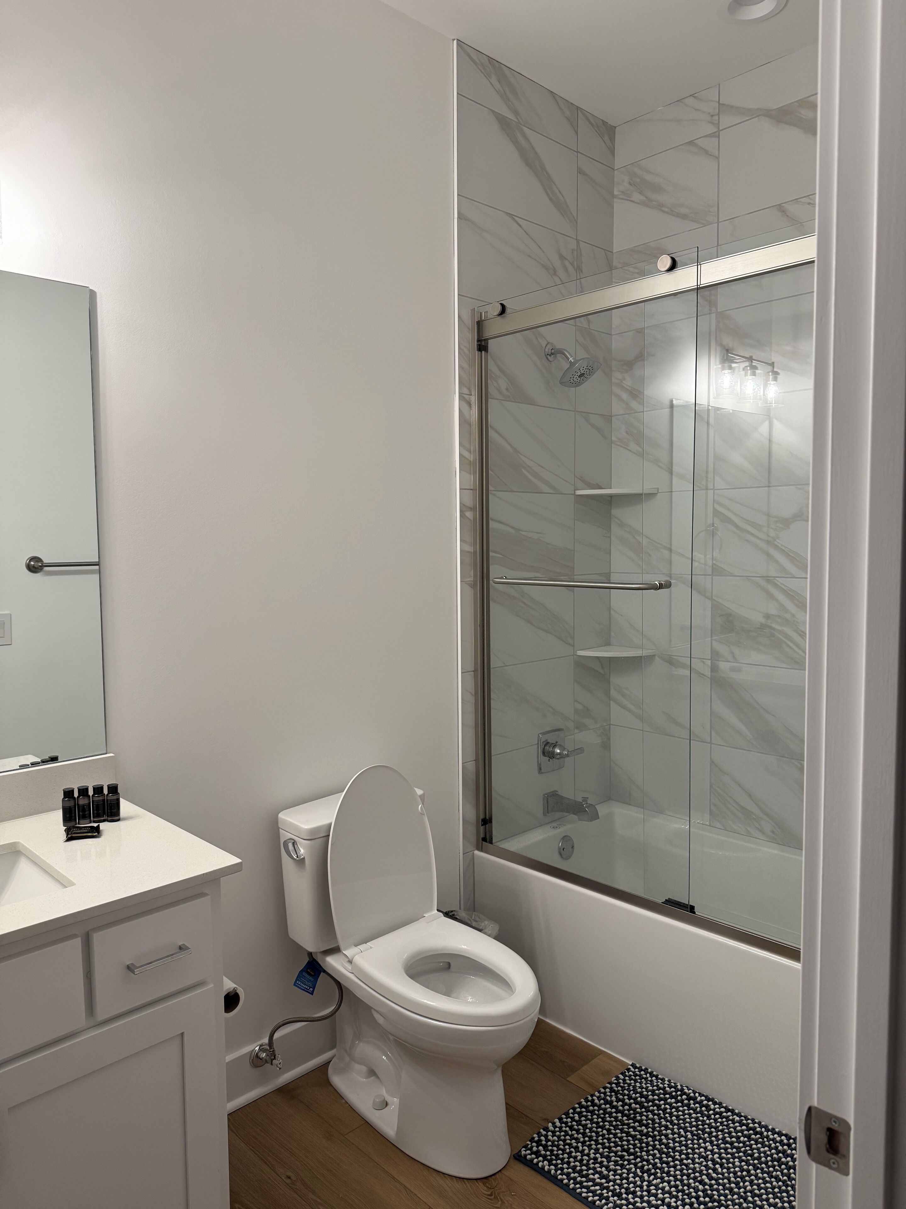 A modern bathroom with a toilet, sink, and glass-enclosed shower.