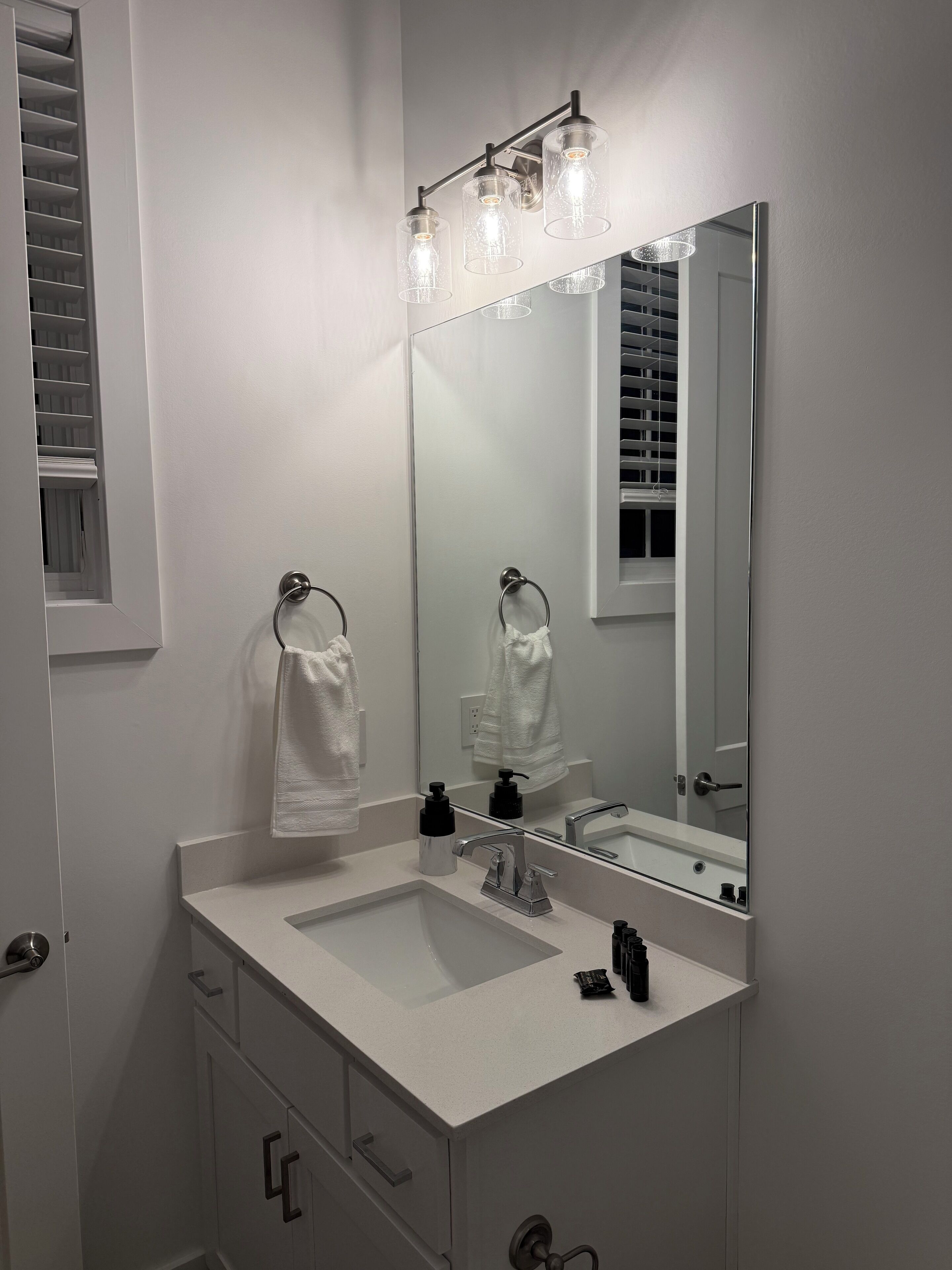 Een moderne badkamer met een witte wastafel, een grote spiegel en een handdoekhouder.