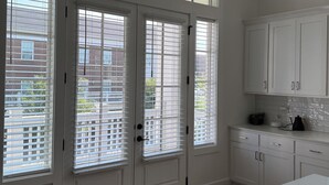 A kitchen with white cabinets, a countertop, and a window with blinds. - 3-bedroom condo in Norton Commons (Prospect)