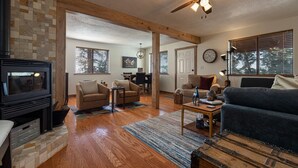 A cozy living room with a fireplace, wooden flooring, and a ceiling fan. - Strawberry Summit Cabin Retreat (Duck Creek Village)