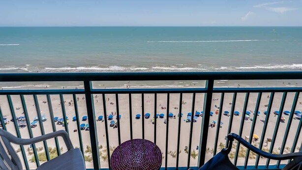 A balcony with a view of the beach, rows of umbrellas, and chairs. - New Direct Oceanfront View,Sandcastle South,Pools! (Myrtle Beach)