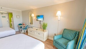 A hotel room with two beds, a desk with a chair, a TV, and a sofa.