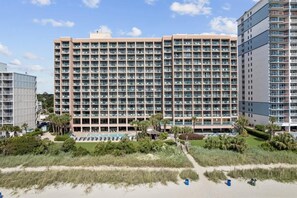 Un grande hotel con diversi piani, una piscina e una spiaggia.