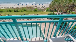 A pool area with a view of the beach and palm trees.