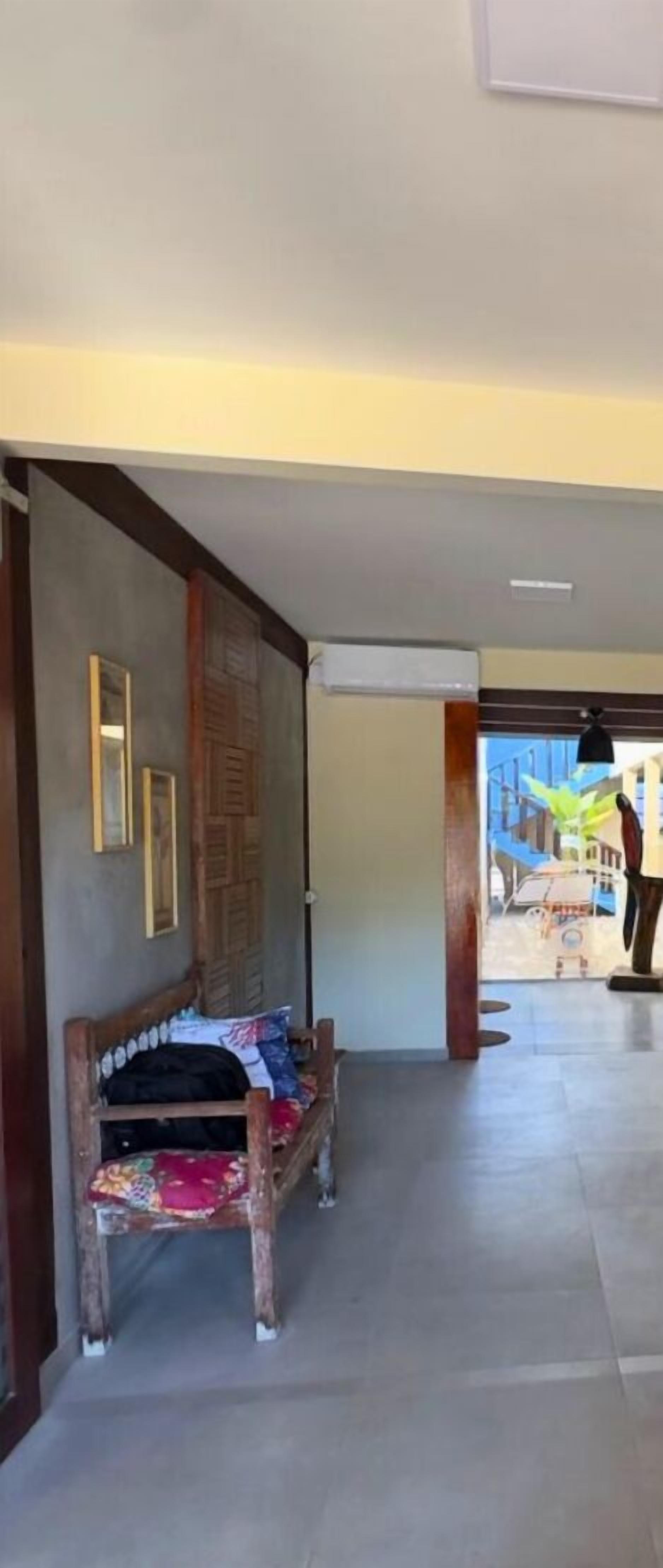 A hallway with a wooden bench, a door with a decorative panel, and a view of the outside.
