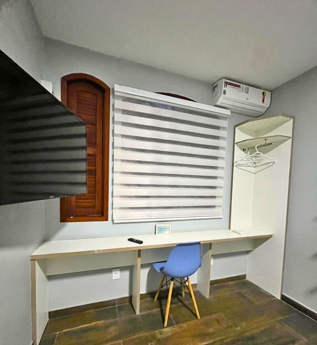 A room with a desk, a blue chair, a wooden door, and a white air conditioning unit.