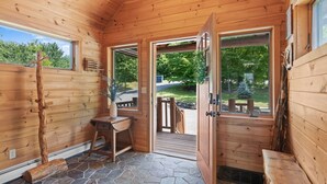 Una cabaña de madera con suelo de piedra, un escritorio de madera y un banco.
