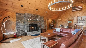 Un salón acogedor con chimenea de piedra, sofá de cuero y lámpara colgante.