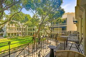 Un patio con jardín, zona de estar al aire libre y un edificio con balcones.