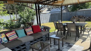 Une terrasse extérieure avec un canapé, des fauteuils et une table.