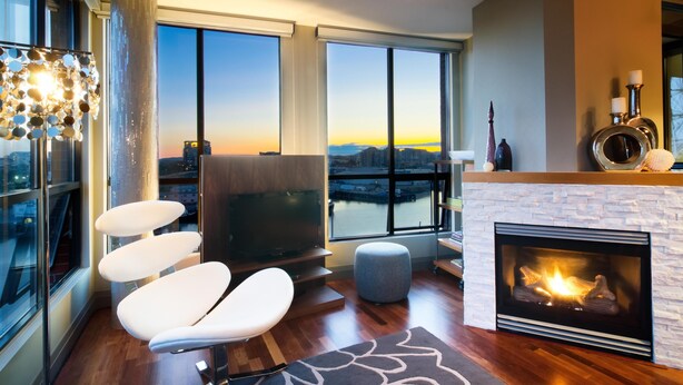 Ein modernes Wohnzimmer mit Kamin, großen Fenstern und Stadtblick sowie zeitgemäßen Möbeln.