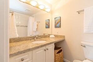 Une salle de bain avec un lavabo en granit, un grand miroir et deux œuvres d’art encadrées accrochées au mur.