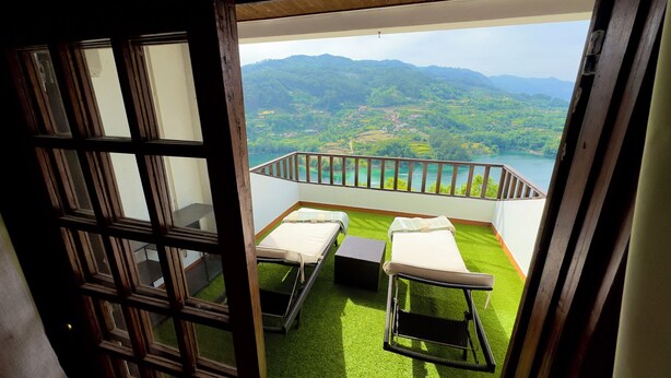 A balcony with two beds and a view of a lake and mountains. - Viewpoint 13 (Caniçada, Braga, Portugal)
