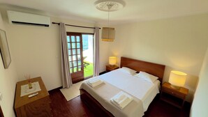 A hotel room with a large bed, two bedside lamps, a wooden nightstand, a small table with a remote control, a window with curtains, and a ceiling light fixture. - Viewpoint 13 (Caniçada, Braga, Portugal)