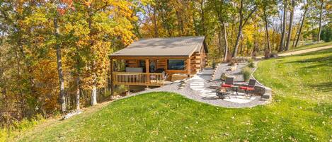 A log cabin with a deck, outdoor seating, and a fire pit.