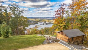 A cabin with a view of a river and surrounding forest.