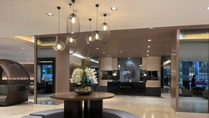 A modern reception area with a round table, a vase of white flowers, and a reception desk. -  Shore Residences MOA by darpm (Pasay)