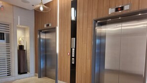 A modern elevator with a digital display, a wooden panel wall, and a floor with beige tiles. -  Shore Residences MOA by darpm (Pasay)