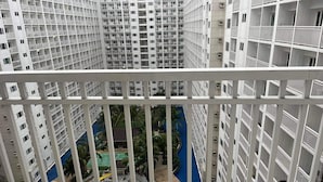 A high-rise building with multiple balconies and a central courtyard featuring a swimming pool and a small bridge. -  Shore Residences MOA by darpm (Pasay)